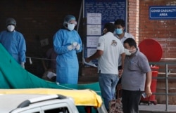 FILE - People speak with a health worker about their relatives at a COVID-designated hospital in New Delhi, India, June 10, 2020.