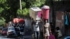 FILE - People carry their belongings along a street as they flee their homes from gang violence, in Port-au-Prince, Haiti, Oct. 26, 2024.