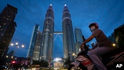 A food delivery rider waits at a traffic junction in front of Twin Towers to deliver food during the movement control order due to the outbreak of the coronavirus disease (COVID-19) in Kuala Lumpur, Malaysia, May 1, 2020. 