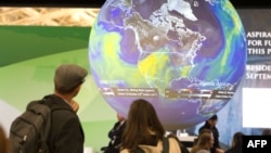 People look at an Earth globe display at the COP21, the United Nations conference on climate change in Le Bourget, Dec. 10, 2015.