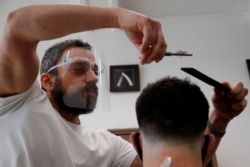 Chris, owner of Stag Co barbers, cuts hair as hairdresser shops reopen, as the coronavirus disease (COVID-19) restrictions ease, in Herford, Britain, Apr. 12, 2021.