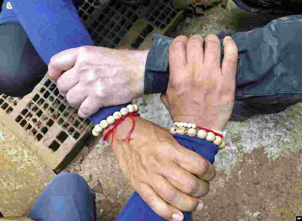 This undated photo released via the Thailand Navy SEAL Facebook page July 8, 2018, shows rescuers hands locked with a caption reading "We Thai and the international teams join forces to bring the young Wild Boars home."