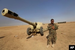 FILE - A Kurdish peshmerga fighter stands next to a firearm in Mahmoudiyah, Iraq, where fighters took control of it from the Islamic State group while patrolling in the northern village, Oct. 1, 2014.