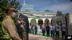 FILE - A member of security forces stands guard while Muslim worshipers queue to enter a mosque for Friday prayers in Rabat, Morocco, Oct. 16, 2020.