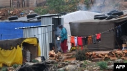 FILE - A Syrian refugee woman stands outside a tent at a makeshift camp in the village of Kfarkahel, in the Kura district near the northern city of Tripoli, Dec. 11, 2013