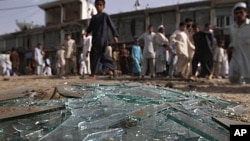 Afghans walk pass the derbies at the site of a bomb explosion in Laghman province east of Kabul, Afghanistanm, June 11, 2011.