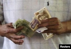 A customer counts Chinese Yuan notes at a market in Beijing, Aug. 12, 2015.