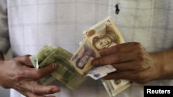 FILE - A customer counts Chinese Yuan notes at a market in Beijing, Aug. 12, 2015. 