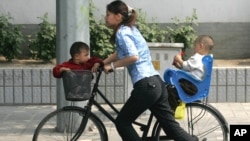 Seorang perempuan China membawa 2 anaknya dengan bersepeda di Beijing (foto: dok). Diperkirakan 1 dari 4 perempuan China mengalami KDRT oleh pasangannya. 
