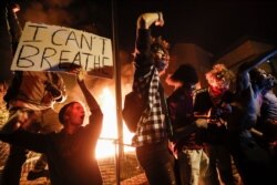 Protesters demonstrate outside a burning Minneapolis 3rd Police Precinct, May 28, 2020, in Minneapolis.