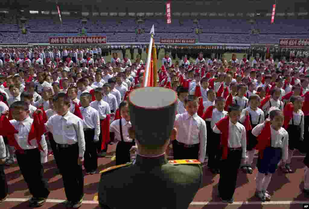 North Korean children hold up red scarves to be tied around their necks during an induction ceremony into the Korean Children's Union held at a stadium in Pyongyang, April 12, 2013.
