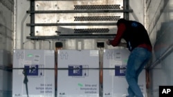 Petugas kesehatan memeriksa kotak vaksin AstraZeneca COVID-19 di dalam truk, yang dikirim ke Idlib melalui perlintasan perbatasan dengan Turki, di Bab Al-Hawa, Suriah barat laut, 21 April 2021. 