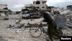 A man walks with his bicycle at a damaged site in the besieged town of Douma, Eastern Ghouta, in Damascus, Syria, March 30, 2018.