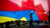 Un joven camina bajo una gran bandera venezolana durante un mitin pro gobierno en Caracas, Venezuela. Febrero 25, 2014.
