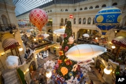 FILE - Customers walk past Christmas trees decorated for New Year celebrations in the Moscow GUM department store in Moscow, Russia, Nov. 29, 2017.