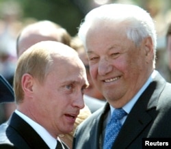 FILE - Russian President Vladimir Putin speaks as former Russian president Boris Yeltsin, right, smiles in Red Square in Moscow, June 12, 2004.