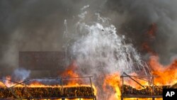 FILE - Smokes and flames billow from burning drugs during a destruction ceremony of seized narcotic drugs in outskirts of Yangon, Myanmar, Monday, June 26, 2017.