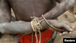 FILE - A prisoner, suspected of being a member of insurgent group Boko Haram, sits with his arms tied behind his back in the field base of Chadian soldiers in Gambaru, Nigeria, Feb. 26, 2015.