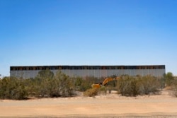 FILE - Government contractors erect a section of border wall along the Colorado River, Sept. 10, 2019, in Yuma, Ariz.