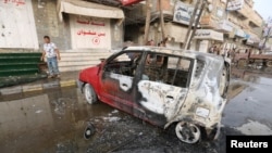 FILE - A man stands by a car damaged by a strike near al-Thawra Hospital in Hodeidah, Yemen, Aug. 2, 2018.