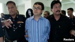 FILE - Abdul Razak Abdullah Baginda, center, is escorted by policemen as he leaves the courtroom in Shah Alam outside Kuala Lumpur, Sept. 3, 2007. Razak, 46, a close aide of Najib Razak, has been accused of involvement in the murder of 28-year-old Mongolian model.