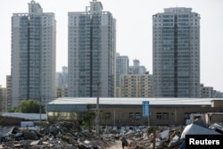 Migrant worker Wang Jun carries scrap material she collected from debris of demolished buildings at the outskirts of Beijing, China, Oct. 1, 2017.