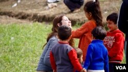 A volunteer plays with refugee kids in Idomeni on the Greek-Macedonian border. (J. Dettmer/VOA)
