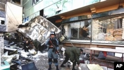 An Afghan policeman stands guard as others examine the damaged building of shopping complex after suicide bomber detonated a cache of explosives inside the building in Kabul, Afghanistan, February 14, 2011