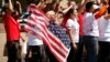 FILE - A woman holds up a U.S. flag as she other anti-deportation protesters chant in front of the White House in Washington.