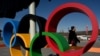 A man walks behind the Olympic Rings in Beijing on Jan. 28, 2022, ahead of the 2022 Beijing Winter Olympic Games. 