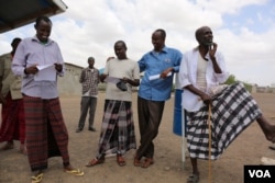 Somali Ahmed Omar Bihi and fellow refugees in Kakuma refugee camp check to see what names appear on a list for an interview with the International Organization for Migration (IOM) for potential U.S. resettlement.