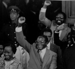 FILE - Zimbabwean Premier Robert Mugabe gives a triumphant salute as he emerges from Parliament following its official opening, May 14, 1980.