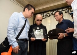 FILE - Liu Xia, wife of jailed Nobel Peace Prize winner and Chinese dissident Liu Xiaobo, holds a portrait of him during his funeral in Shenyang in northeastern China's Liaoning Province, July 15, 2017.