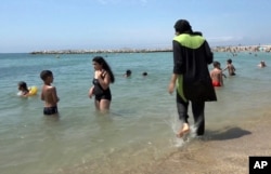 FILE - In this Aug. 4, 2016 file photo made from video, Nissrine Samali, 20, gets into the sea wearing traditional Islamic dress, in Marseille, southern France. The French resort of Cannes has banned full-body, head-covering swimsuits worn by some Muslim wo