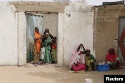 FILE - Women watch Cameroonian military patrol in Kerawa, Cameroon, March 16, 2016. Kerawa, on the border with Nigeria, was subject to frequent Boko Haram attacks.