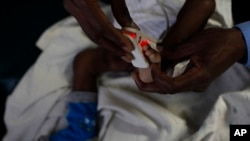 FILE - A doctor puts a heart monitor on the foot of a baby who is suffering from severe malaria in the Siaya hospital in western Kenya.