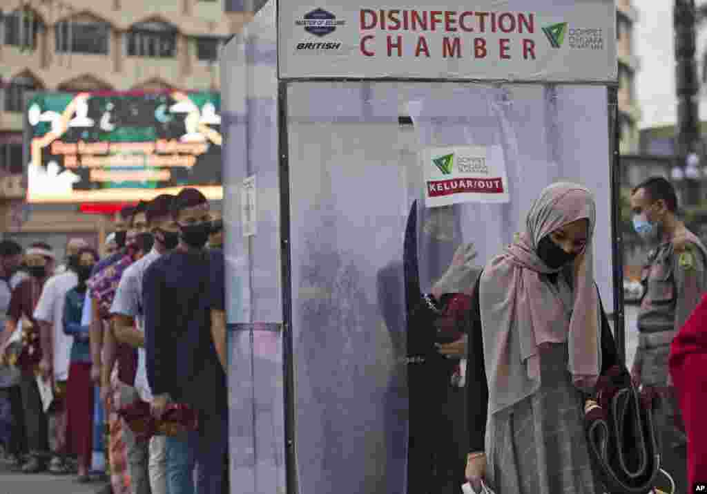 Muslims queue up to enter a disinfection chamber set up as a precaution against the new coronavirus outbreak, prior to entering Al Mashun Grand Mosque&#39;s compound to attend an Eid al-Adha prayer in Medan, North Sumatra, Indonesia.