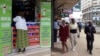 Pedestrians walk past an M-Pesa shop in downtown Nairobi, Kenya, May 12, 2009. 