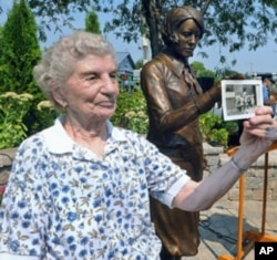 Next to the 'Radium Girls' statue, Rose Baima, who worked at Luminous Process, holds a photo of her and her co-workers during the 1940's, September 2, 2011.