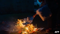 An election official burns ballots after the counting has finished at a voting station in Libreville on November 16, 2024. Gabon on Saturday held a referendum on a new constitution after a coup ended 55 years of rule by the Bongo dynasty in the oil-rich nation. 