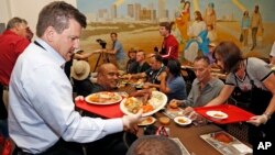 Arizona Cardinals team president Michael Bidwill, left, joins other players and staff of the Cardinals NFL football team as they serve Thanksgiving dinner at the Phoenix Rescue Mission at the 15th annual 'Feed the Hungry' event, Nov. 21, 2016, in Phoenix.