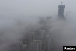 Buildings are seen shrouded in heavy haze at Qingdao development zone, Shandong province, February 25, 2014.