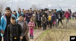 FILE - Refugees and migrants, mostly from Afghanistan, walk towards the transit center for refugees near the northern Macedonian village of Tabanovce, after being returned from Serbia, Monday, Feb. 22, 2016.