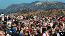 A crowd gathers in front of the Hollywood sign at the Griffith Observatory to watch the solar eclipse in Los Angeles on Monday, Aug. 21, 2017. (AP Photo/Richard Vogel)