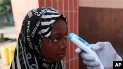 Wani Malami na amfani da na’urar auna zafin jiki domin neman alamun cutar Ebola.