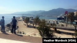 Refugees and migrants watch as a boat departs to Athens, which would be the next step in their journey towards countries like Germany and Sweden, if they could get on, in Lesbos, Greece, April 2, 2016.