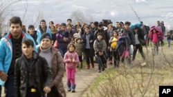 FILE - Refugees and migrants, mostly from Afghanistan, walk toward the transit center for refugees near the northern Macedonian village of Tabanovce, after being returned from Serbia, Feb. 22, 2016.