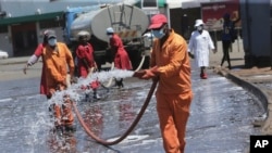 Harare City Council workers disinfect a bus terminal, in Harare, Zimbabwe, April, 1, 2020. 