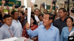 FILE - Cambodian Prime Minister Hun Se looks his ballot at a polling station in Takhmua, Kandal province, southeast of Phnom Penh, Cambodia, Sunday, July 29, 2018. 
