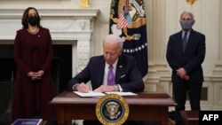 U.S. President Joe Biden signs executive orders as part of the COVID-19 response as U.S. Vice President Kamala Harris, left, and Director of NIAID Anthony Fauci look on in the State Dining Room of the White House in Washington, Jan. 21, 2021. 